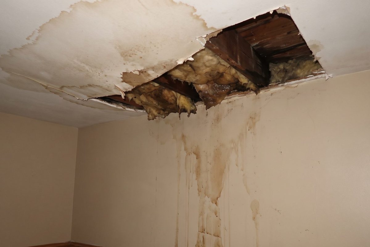 A collapsed ceiling and water staining down an interior wall